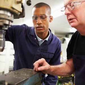 Engineering trainer showing Apprentice how to use tools