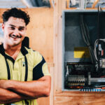 Electrical student standing beside open switchboard during training