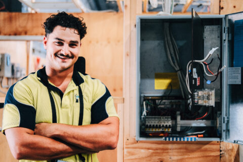 Electrical student standing beside open switchboard during training