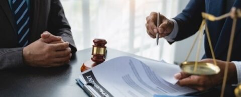 Lawyers at a desk with a gavel, documents, and justice scales.