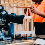 Worker in high-vis shirt assembling a wooden frame in a workshop.