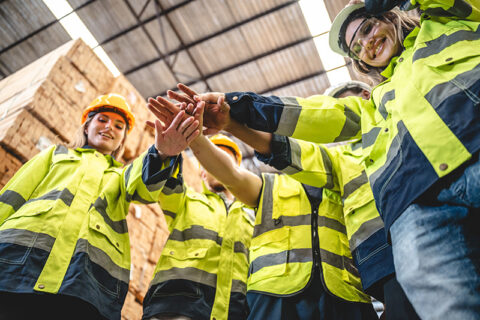 Construction team huddling together in a warehouse.