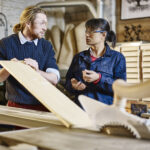 Two people discussing wood in a workshop