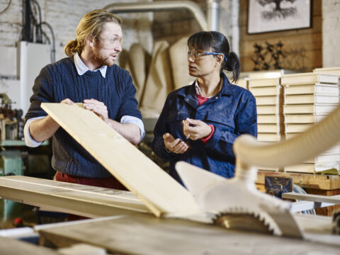 Two people discussing wood in a workshop