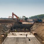 Construction workers and excavators working on large building site