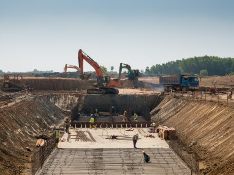 Construction workers and excavators working on large building site
