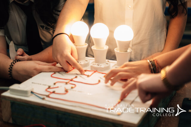 Students learning electrical wiring with illuminated light bulbs