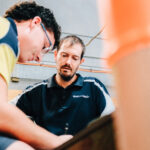 Trade instructor guiding student during hands-on workshop training