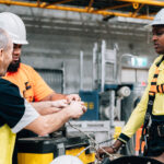 Workers in high-vis gear and hard hats training with a rope.