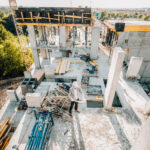 Architect in a hard hat reviewing plans at a construction site.