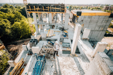 Architect in a hard hat reviewing plans at a construction site.