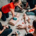 First aid training session practicing CPR on adult and infant mannequins