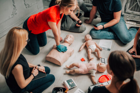 First aid training session practicing CPR on adult and infant mannequins