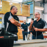 Trainers talking in workshop, one holding tools
