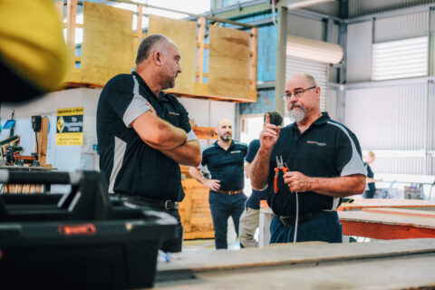 Trainers talking in workshop, one holding tools