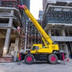 Large yellow mobile crane operating at an urban construction site.