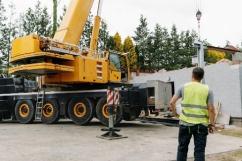 Crane truck on site with worker in hi-vis vest