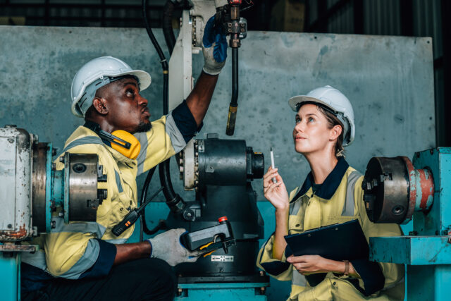 Industrial trainees inspecting machinery during hands-on skills training