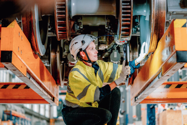 Female technician inspecting train wheel assembly