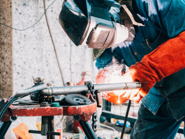Welder wearing protective gear performing metal welding work