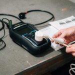 Hands testing a power plug with a portable appliance tester.