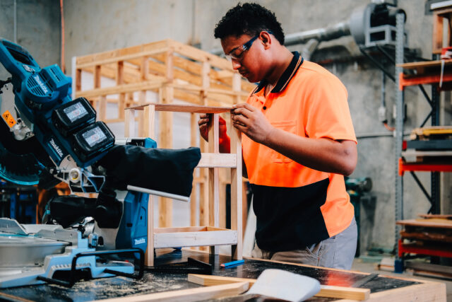 Carpentry student assembling wooden furniture in training workshop