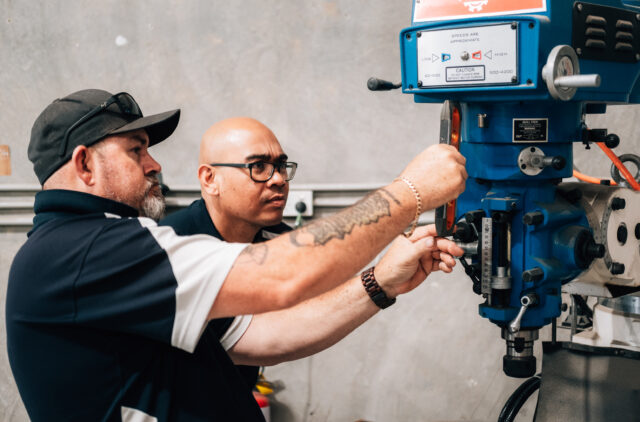 Two men adjusting industrial drill press