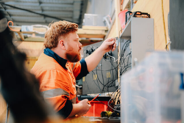 Electrical apprentice testing wiring inside control panel