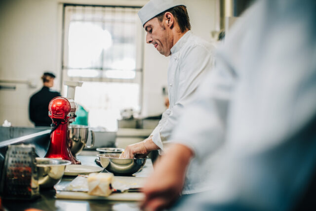 Professional chef preparing dough in commercial kitchen workspace
