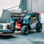 Manitou telehandler moving a pallet with an instructor nearby.